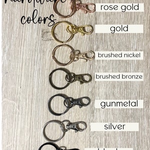 May include: Hardware colours for keychains, shown as a series of key rings with different coloured clasps.  The colours are rose gold, gold, brushed nickel, brushed bronze, gunmetal, silver, and black.