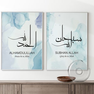 May include: Two framed prints with blue watercolor backgrounds and Arabic calligraphy. The text on the left print reads "Alhamdulillah" and "Praise be to Allah". The text on the right print reads "Subhan Allah" and "Glory be to Allah".