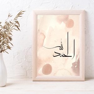 May include: A framed print with a watercolor background in shades of pink and brown. The print features the Arabic calligraphy "Alhamdulillah" in black ink.