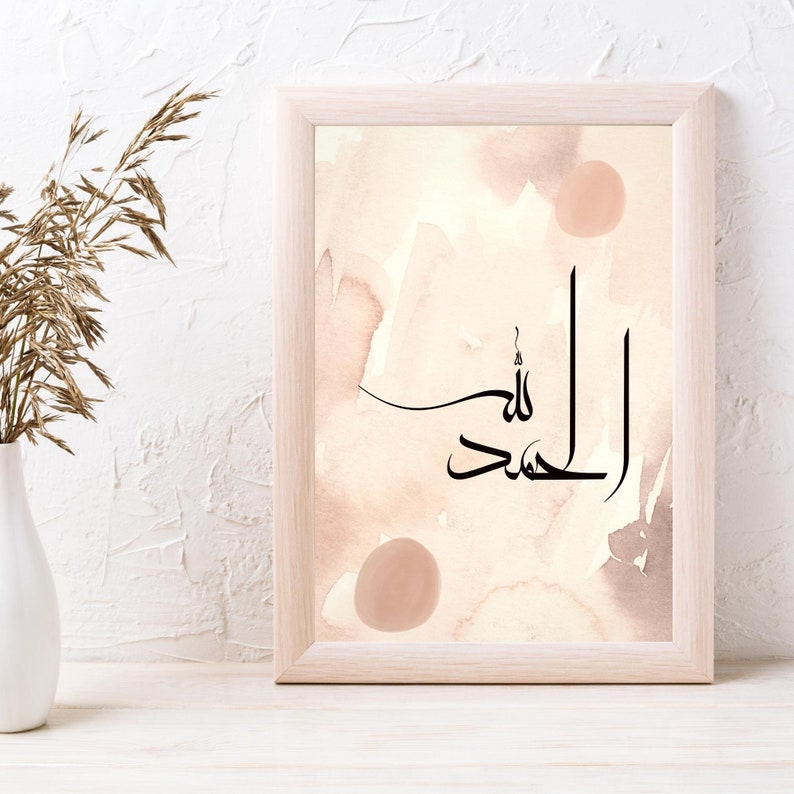 May include: A framed print with a watercolor background in shades of pink and brown. The print features the Arabic calligraphy "Alhamdulillah" in black ink.