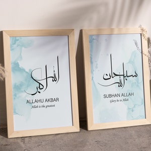 May include: Two framed prints with a light blue watercolor background. The left print features the Arabic text "Allahu Akbar" with the English translation "Allah is the greatest". The right print features the Arabic text "Subhan Allah" with the English translation "Glory be to Allah".