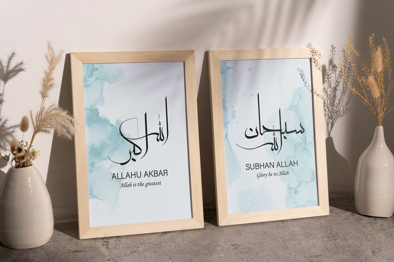May include: Two framed prints with a light blue watercolor background. The left print features the Arabic text "Allahu Akbar" with the English translation "Allah is the greatest". The right print features the Arabic text "Subhan Allah" with the English translation "Glory be to Allah".
