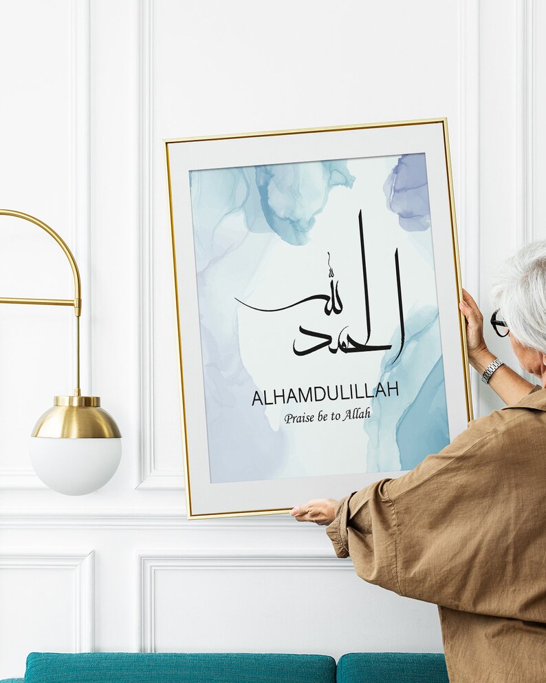 May include: A framed print with a blue watercolor background and black calligraphy that reads "Alhamdulillah" with the English translation "Praise be to Allah".