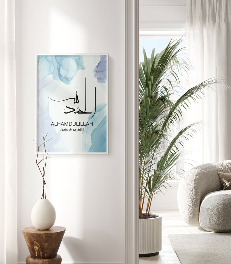 May include: A framed print with a blue watercolor background and the Arabic calligraphy for "Alhamdulillah" in black. The text "Praise be to Allah" is written below the calligraphy.