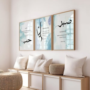 May include: Three framed prints with Arabic calligraphy and English text. The prints are on a light blue background with white watercolor accents. The text on the prints reads "Love", "Gratitude", and "Patience".