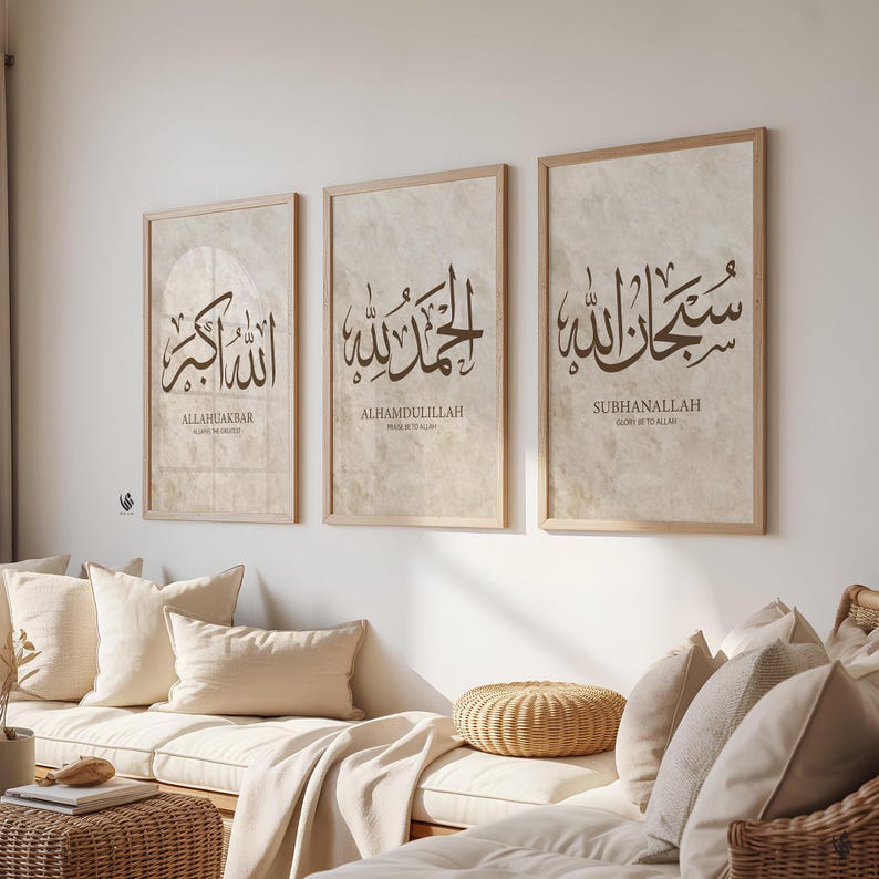 May include: Three framed art prints with Arabic calligraphy in brown script on a beige background. The prints are in light wood frames and are hung on a white wall. The text includes "ALLAHUAKBAR", "ALHAMDULILLAH", and "SUBHANALLAH".