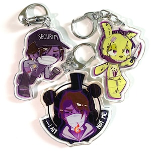 Puede incluir: Tres llaveros de acrílico coloridos con personajes del popular videojuego Five Nights at Freddy's. Los llaveros son morados, verdes y amarillos con contornos negros. Los personajes llevan máscaras y tienen el texto "Security", "I Am" y "Not Me" en sus llaveros.
