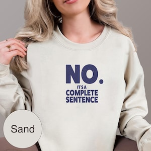 May include: Sand-coloured sweatshirt with the navy blue text "NO. IT'S A COMPLETE SENTENCE." The sweatshirt is a neutral colour and has a crew neck. The text is centred on the front of the sweatshirt.