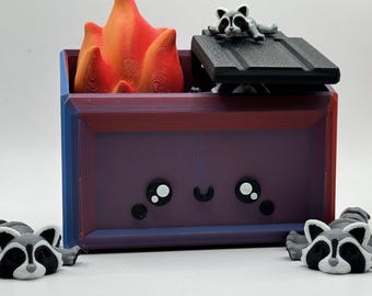 May include: A small, purple, wooden box with a cute cartoon face. The box has a black lid with a raccoon figurine on top. There are three raccoon figurines around the box.