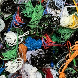 Può includere: Primo piano di un ammasso di cavi e corde colorati e aggrovigliati. I cavi sono di vari colori, tra cui nero, bianco, verde, rosso, blu e arancione.
