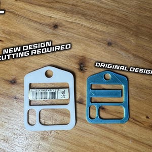 May include: Two flat, rectangular plastic components with rounded corners and a top hole. The left white component is labeled 'NEW DESIGN NO CUTTING REQUIRED' and features a barcode. The right blue component is labeled 'ORIGINAL DESIGN'.