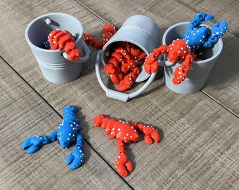 May include: A collection of red and blue lobster figurines with white spots, some are in gray buckets.