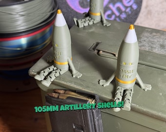 May include: Three olive green articulated figurines shaped like 105mm artillery shells with white tips and gold bands. Each figure has jointed arms and legs, sitting on a large olive green metal ammunition box. Text reads 105MM ARTILLERY SHELLS!