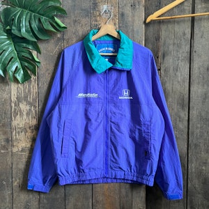May include: A purple windbreaker jacket with a teal collar and zipper. The jacket has the words "Modulo" and "Honda" printed on the front.