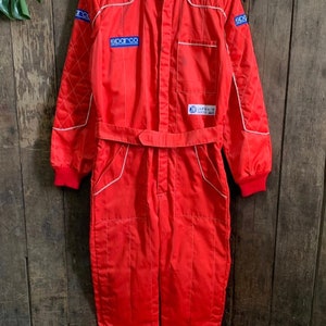 May include: Red racing suit with white piping and Sparco and Alfa Romeo logos.