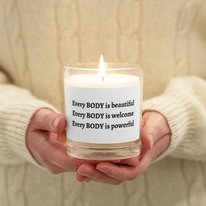 Op de afbeelding: Een witte kaars in een glazen pot met een label waarop staat "Every BODY is beautiful, Every BODY is welcome, Every BODY is powerful".