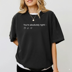 May include: Black short-sleeved t-shirt with the text "You're absolutely right!" and social media icons. The shirt has a white undershirt peeking out at the neckline. A gold necklace is visible.