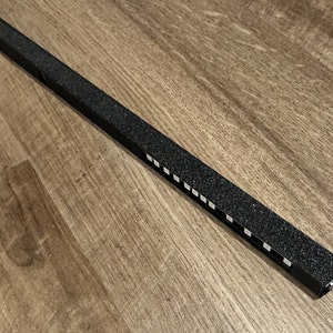 May include: A black light strip with a textured surface and a row of white LED lights.