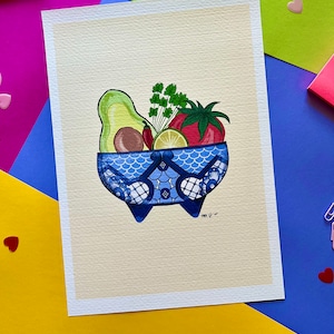 May include: A blue and white ceramic bowl with a scalloped rim and four feet, filled with a green avocado, a red tomato, a lime, and green cilantro.
