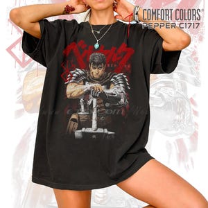May include: Black Comfort Colors t-shirt featuring a graphic of a warrior with a sword, with the text "BERSERK" in red. The shirt has a vintage look and feel, with the text "COMFORT COLORS PEPPER C1717" printed on the upper right.