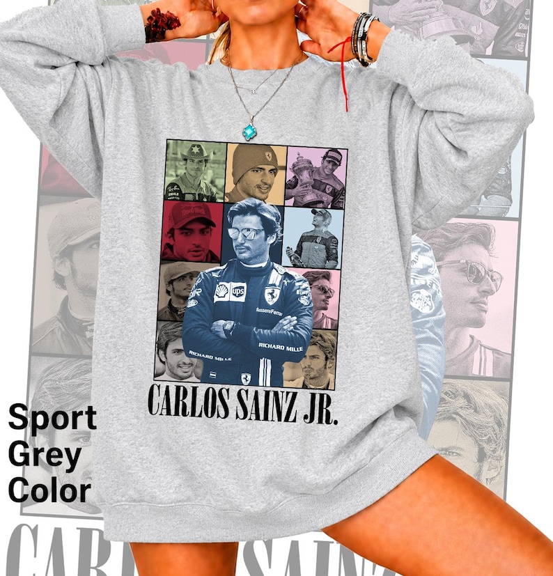 Peut inclure: Un sweat-shirt gris clair &agrave; col rond arborant un grand collage graphique central de Carlos Sainz Jr. dans diverses poses et tenues de course. Le texte CARLOS SAINZ JR. est imprim&eacute; en noir sous les images. Le sweat-shirt a des manches longues.