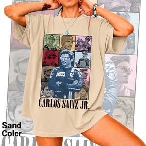 Peut inclure: Un t-shirt couleur sable pr&eacute;sentant un collage de photographies de Carlos Sainz Jr. dans divers contextes de course. L'image centrale montre le pilote dans une combinaison bleue avec des logos de sponsors. Le texte CARLOS SAINZ JR. est imprim&eacute; en noir.