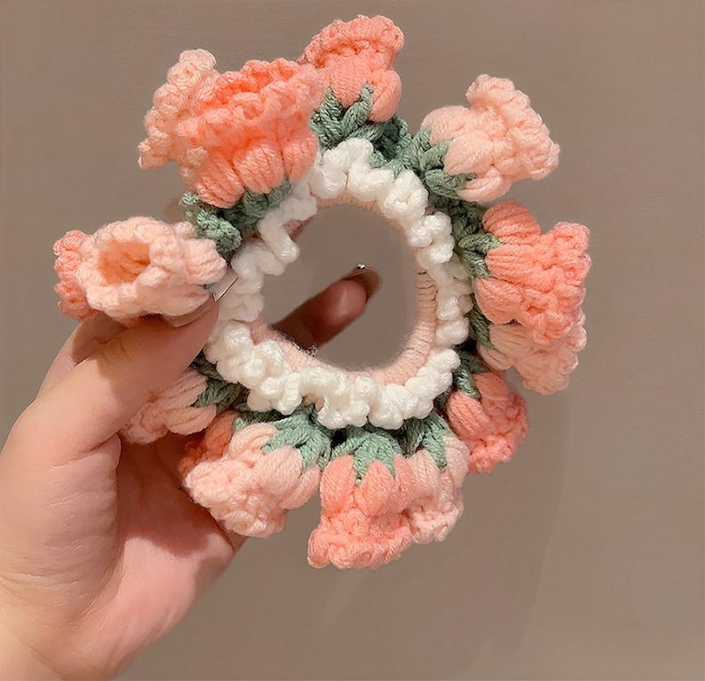 May include: A pink and green crocheted hair scrunchie with a flower design.