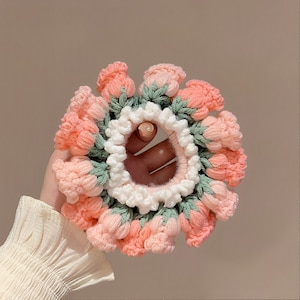 May include: A pink and green crocheted hair scrunchie with a flower design.