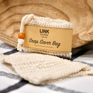 May include: A beige soap saver bag with a brown label that reads "Link Farm John 14:6 Soap Saver Bag".