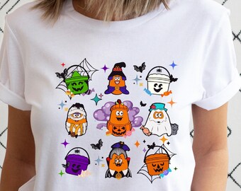 May include: White t-shirt with a Halloween-themed design featuring various characters dressed as ghosts, witches, and pumpkins. The characters are holding buckets with candy and other Halloween treats.