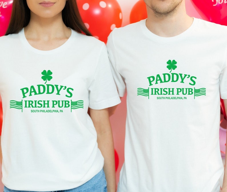 May include: Two white t-shirts with a green shamrock and the text "Paddy's Irish Pub" and "South Philadelphia, PA".