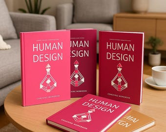 May include: A collection of "Human Design" coaching workbooks in various shades of pink and red. The books feature the title in large, silver lettering, along with a geometric illustration. The books are arranged on a wooden table.