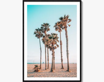 May include: A framed vertical wall art print featuring a sandy beach with several tall palm trees under a clear light blue sky. The scene captures the natural textures of the tree trunks and fronds against the bright horizon of the ocean.