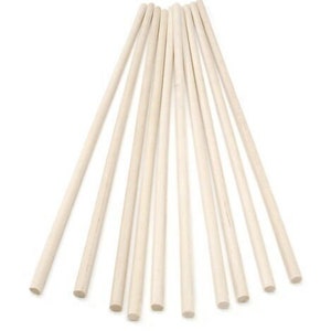 May include: A collection of light-coloured wooden dowels, arranged in a fan shape against a white background. The dowels are cylindrical and appear to be unfinished, with a natural wood grain visible. They are likely used for crafts or construction.