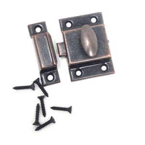 May include: A bronze-coloured latch with an oval handle and matching rectangular strike plate. Includes six black screws for installation. The hardware is designed for cabinets, boxes, or other small projects.