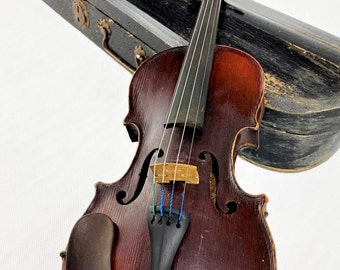 May include: A vintage violin with a dark brown finish and a black case. The violin has four strings and a black chin rest. The case is made of wood and has a worn finish.