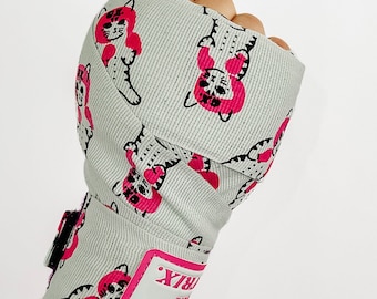Puede incluir: Vendas de boxeo grises con estampado de gato rosa y el texto "RBX" en la correa de la muñeca.
