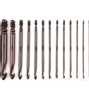 May include: A set of fifteen dark brown wooden crochet hooks arranged in descending order of size. Each hook features a grooved handle and is clearly marked with its specific metric size, ranging from 25.0mm down to 3.0mm, printed on the shaft.