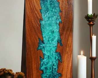 Könnte beinhalten: Rechteckiges Wandkunstwerk aus Holz mit einem Fluss aus türkisfarbenem Harz in der Mitte. Das Holz hat eine satte braune Farbe, und das Harz hat ein strukturiertes, fließendes Aussehen. Das Kunstwerk wird auf einer Holzoberfläche präsentiert. Ca. 60 cm hoch.