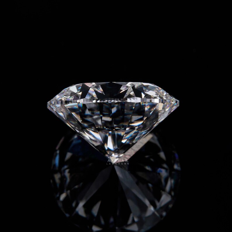 May include: A large, clear diamond with many facets, reflecting light. The diamond is set against a black background, creating a dramatic contrast. The image highlights the brilliance and clarity of the gemstone.