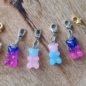 Könnte beinhalten: Fünf bunte Gummibärchen-Anhänger mit silbernen und goldenen Karabinerhaken. Die Anhänger sind im Ombre-Stil gehalten, mit rosa, blauen und braunen Farben.