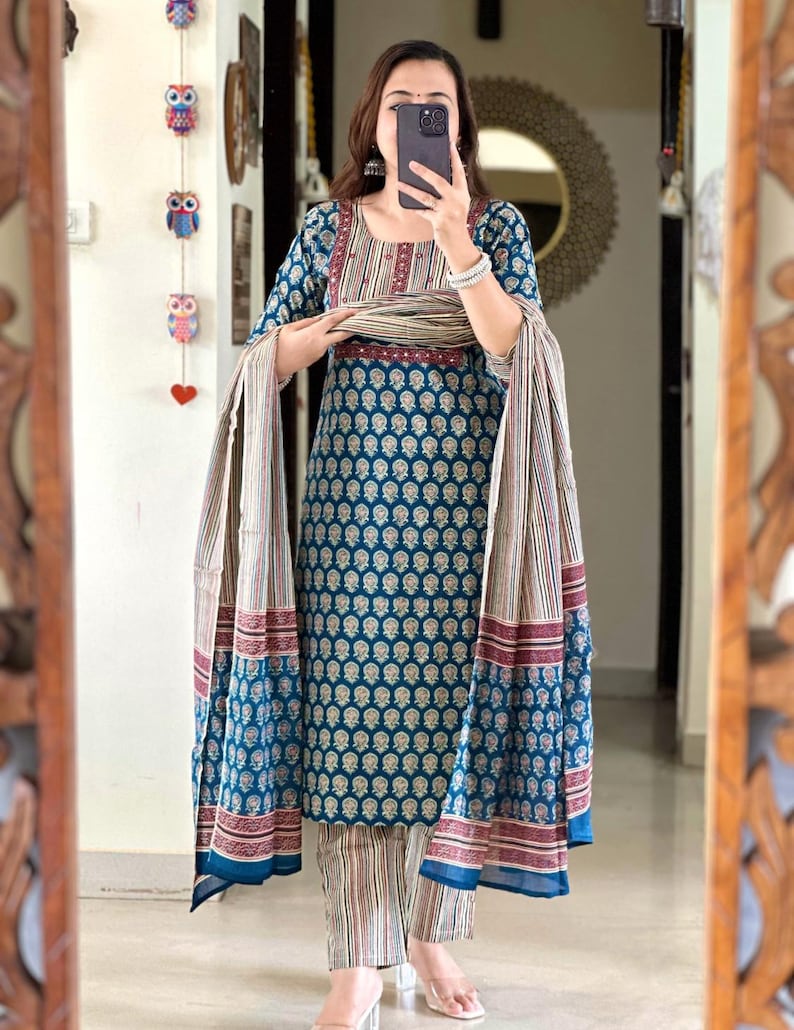 May include: A teal blue and white printed kurta with a matching palazzo pant and dupatta. The kurta has a maroon and white striped neckline and a maroon border. The dupatta has a maroon and white striped border.