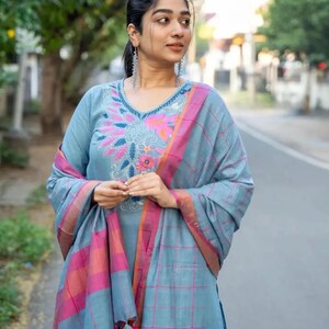 Peut inclure: Une femme portant une kurta bleu clair avec des broderies roses et orange et un dupatta bleu clair assorti avec des carreaux roses et orange.