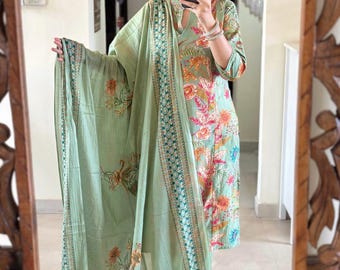 May include: A green floral print kurta with matching pants and a green dupatta with a gold and blue border. The kurta has a V-neck and three-quarter sleeves.