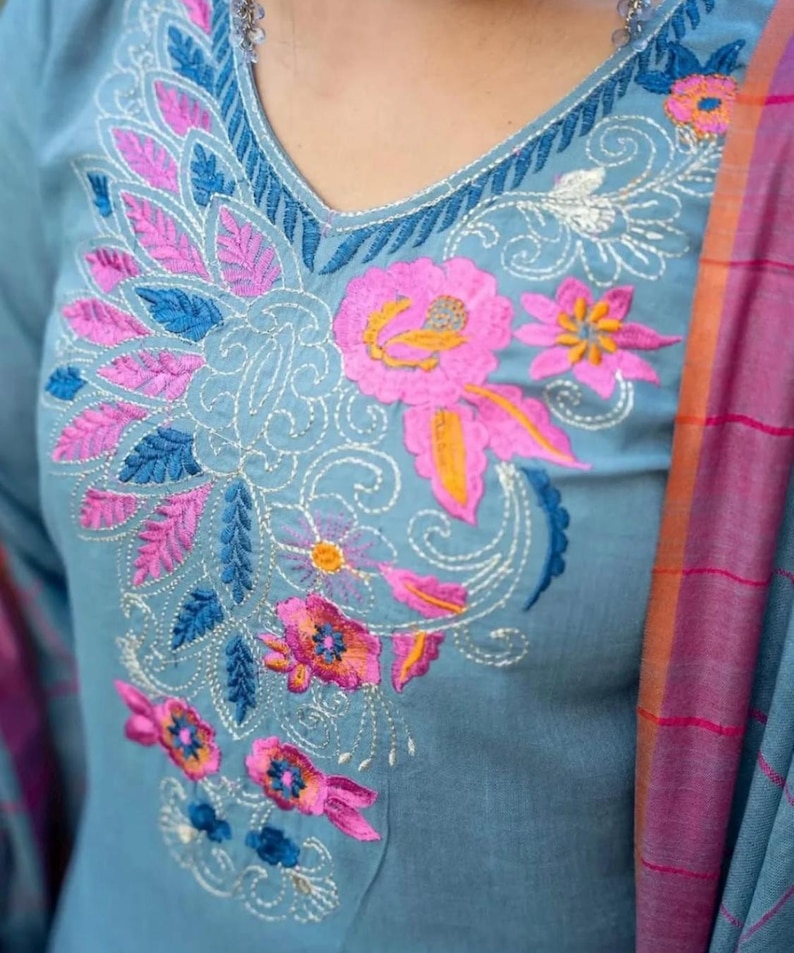 Peut inclure: Une kurta en coton bleu clair avec un motif de broderie florale en rose, bleu et orange. La broderie pr&eacute;sente des d&eacute;tails complexes et un motif paisley.