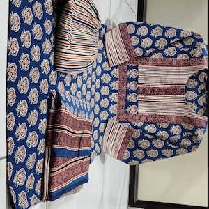 May include: A set of three blue and white patterned fabric squares. The fabric has a paisley design with red and white accents. The squares are folded and arranged on a white tiled floor.