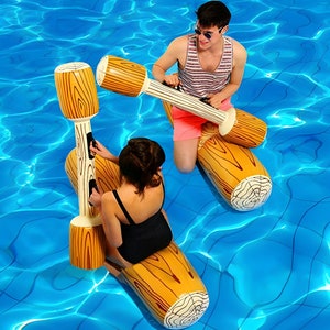 Puede incluir: Dos personas en juguetes inflables para piscina con forma de troncos con detalles de vetas de madera. Los juguetes tienen postes verticales con asas. El agua de la piscina es de un azul brillante, y las personas llevan trajes de baño y gafas de sol.