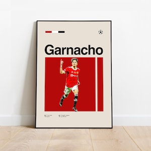 Könnte beinhalten: Ein Retro-Poster mit einem Fußballspieler in einem rot-weißen Trikot, der ein Tor feiert. Das Poster hat einen weißen Hintergrund mit roten und schwarzen Akzenten. Der Name des Spielers, "Garnacho", ist in fetten schwarzen Buchstaben oben auf dem Poster geschrieben. Das Poster enthält auch die Zahl "1" und den Text "Top-Torschütze" und "Gewinner des englischen Ligapokals".