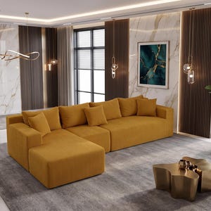 May include: A mustard yellow sectional sofa with multiple throw pillows. The sofa is placed on a gray rug, with a gold-colored coffee table in front. The room has large windows and decorative lighting.