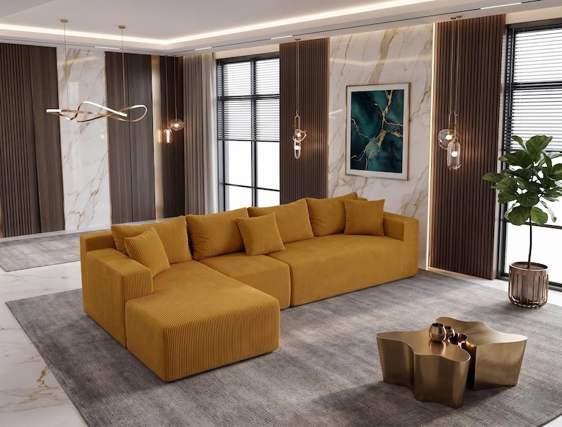 May include: A mustard yellow sectional sofa with multiple throw pillows. The sofa is placed on a gray rug, with a gold-colored coffee table in front. The room has large windows and decorative lighting.
